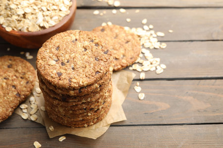 Delicious oatmeal cookies and oat flakes on wooden table, closeup. Space for text