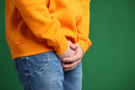 Urology. Man suffering from pain on green background, closeup. Space for text