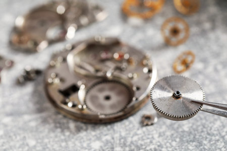 Mechanism of vintage wrist watch, gears and tool on grey table, closeup