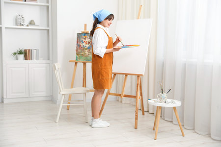 Beautiful woman drawing on canvas at home