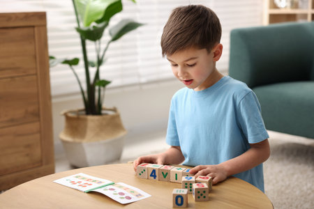 Little boy playing with cubes at wooden table indoors. Educational toy