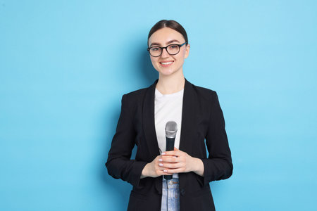 Happy news presenter with microphone on light blue background