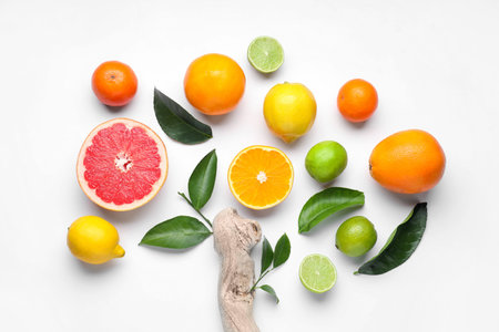 Different fresh citrus fruits, green leaves and snag on white background, flat lay