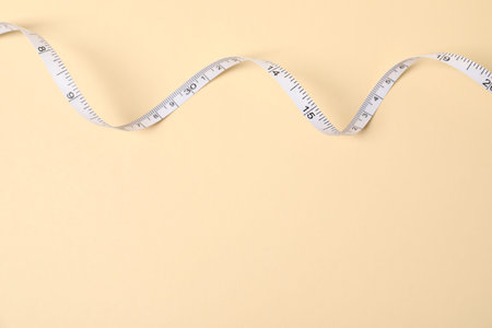 One measuring tape on beige background, top view. Space for text