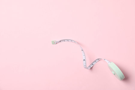 One measuring tape on pink background, top view. Space for text