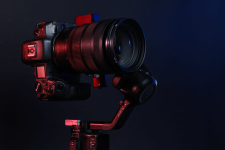 Gimbal stabilizer with camera on black background with red lights, closeup