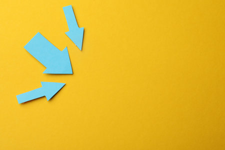 Light blue paper arrows on orange background, flat lay. Space for textの写真素材