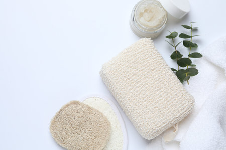 Bath washcloth, natural loofah sponges, scrub, towel and eucalyptus branches on white background,...