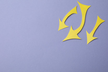 Yellow paper arrows on violet background, flat lay. Space for text