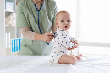 Doctor examining baby with stethoscope in hospital, closeup