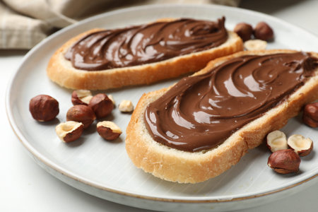 Toasts with chocolate paste and hazelnuts on white table, closeupの写真素材