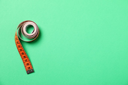 One measuring tape on green background, top view. Space for text