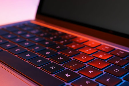 Stylish modern laptop in neon lights, closeup
