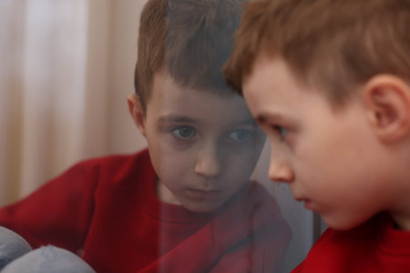 Autism. Little boy with ASD on window sill