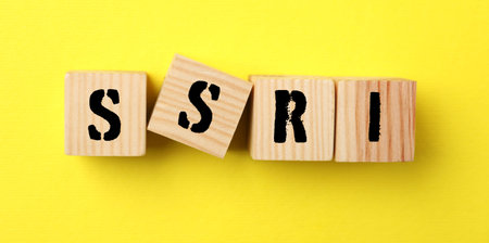 Wooden cubes with SSRI on yellow background, top view. Selective serotonin reuptake inhibitor,...