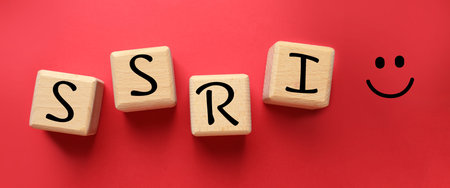 Wooden cubes with SSRI and smiling face on red background, top view. Selective serotonin reuptake...