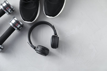 Headphones, sneakers and dumbbells on light grey table, flat lay. Space for textの写真素材