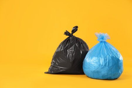 Garbage in colorful bags on yellow background. Space for textの写真素材
