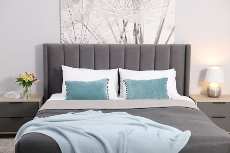 Comfortable bed with fresh linens and nightstand in room
