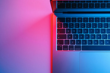 Modern laptop in neon lights on light table, top view. Space for text