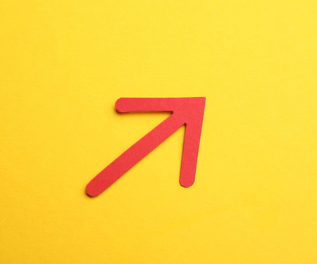 Red paper arrow on yellow background, top view
