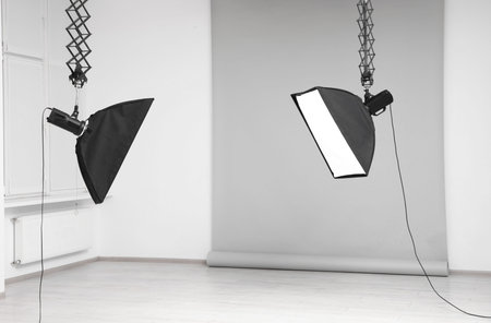 Professional lighting equipment hanging from ceiling in photo studio