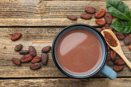 Tasty hot cocoa, beans and powder on wooden table, flat lay