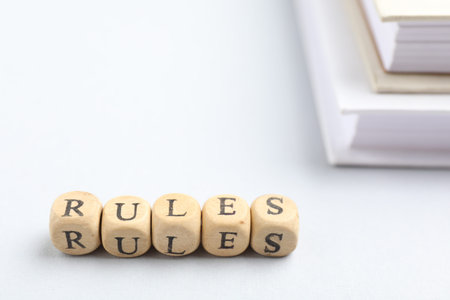 Word Rules made of wooden cubes with letters and books on white table