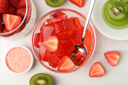 Tasty jelly with strawberries and kiwi on white table, flat lay