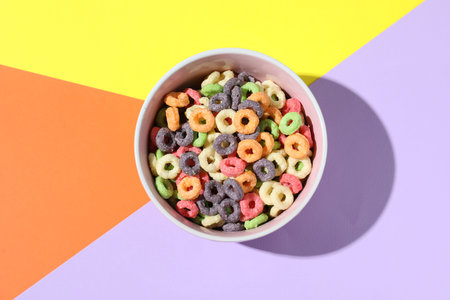 Bowl of delicious cereal on color background, top view