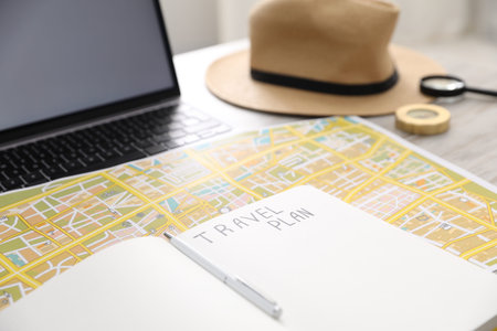 Planning trip. Laptop, notebook and map on table, closeup