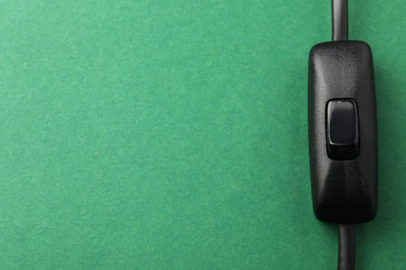 Inline cord switch for lamp on green background, top view. Space for text