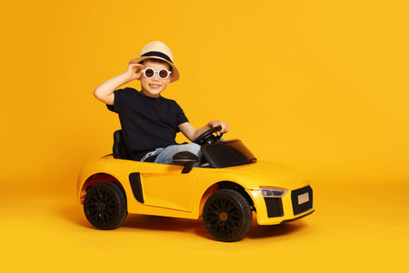 Little child driving toy car on orange background