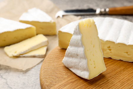 Cut delicious brie cheese and knife on grey table, closeup