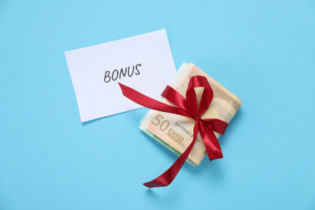Card with word Bonus, bow and euro banknotes on light blue background, top view