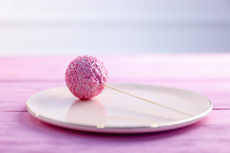 Tasty cake pop on pink wooden table, closeup