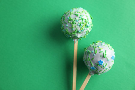Tasty cake pops on green background, top view. Space for text
