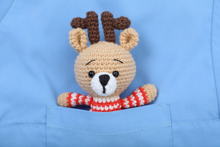 Pediatrician concept. Toy deer in pocket of doctor's uniform, closeup