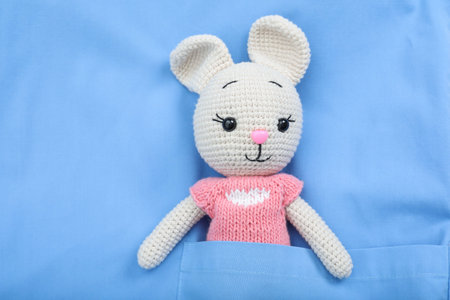 Pediatrician concept. Toy bunny in pocket of doctor's uniform, closeup