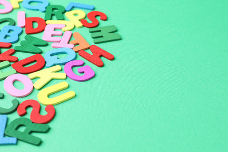 Many colorful wooden letters on green background, closeup. Space for text