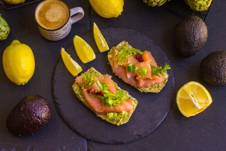 Brown bread sandwich with smoked salmon, avocado topped with chive and pepperの写真素材