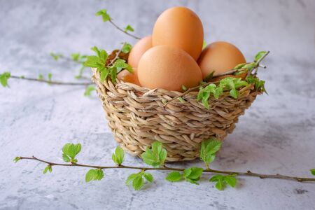 chicken eggs in a basket with green leaves. Easter compositionの写真素材