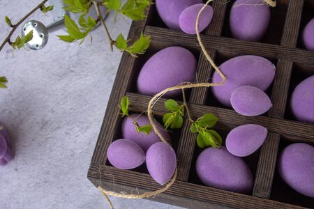Marbled Easter eggs in a wooden box, on a bed of hay, with flowering branches of purple leaf plum...