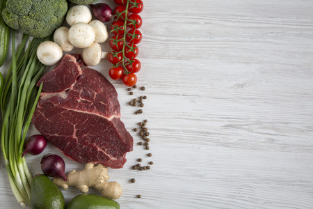 Fresh raw meat beef steak with spices, cherry tomatoes, health food, top view. White wooden...