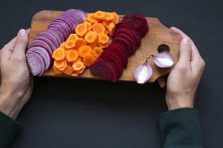 Man holding a board with freshly cut vegetables. Top view.の写真素材