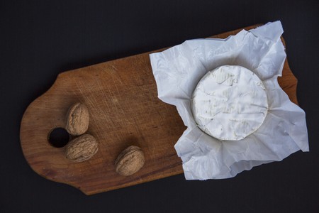 Cheese camembert or brie on dark wooden board with nuts. Dark background. Milk production. Flat lay. From above. Top view. の写真素材