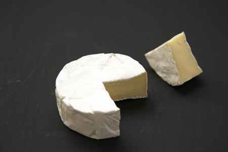 Cheese camembert or brie on dark background. Milk production. Side view. Closeup. 