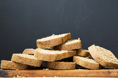 Sliced bread on wooden board. Dark background. Side view. Copy space.