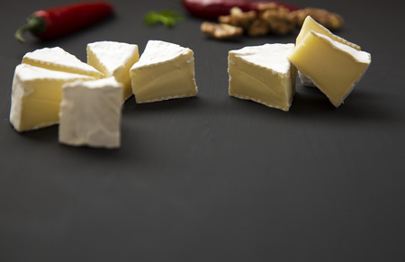 Slices of cheese camembert or brie  with walnuts and chili pepper. Milk production. Side view. 