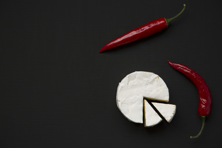 Cheese camembert or brie with chili pepper on dark background. Top view. Flat lay. Copy space. の写真素材